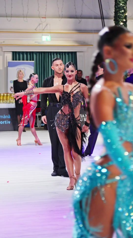 Cuplu într-o rutină latino cu costume turcoaz