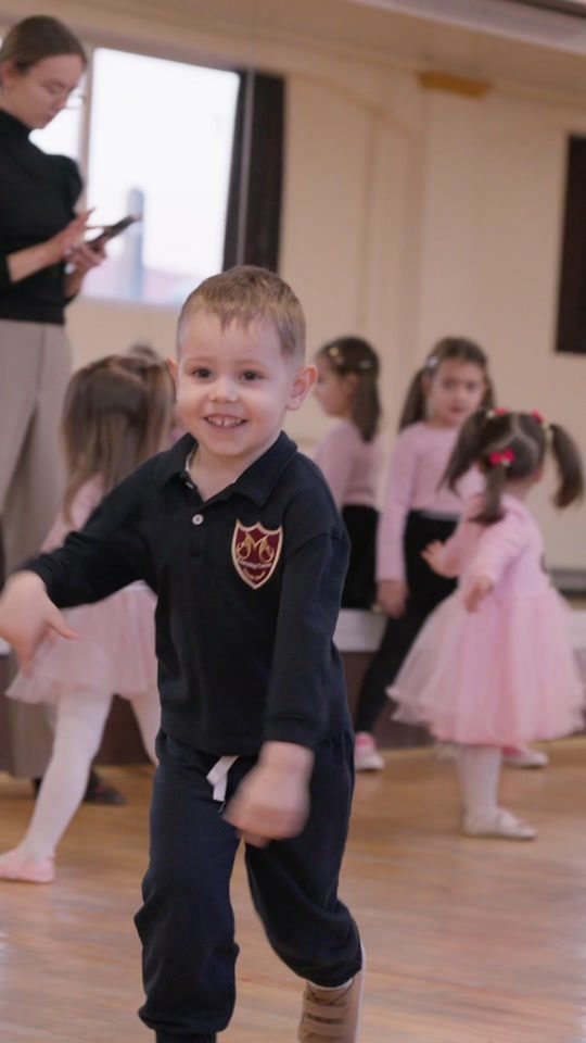 Băiat dansând în față la un recital, alți copii în spate