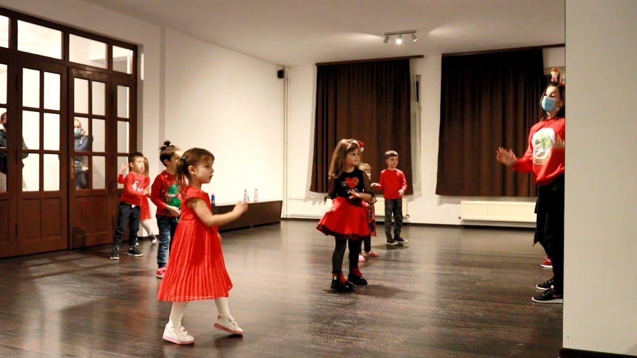 Copii în costume roșii și albe dansând la un recital