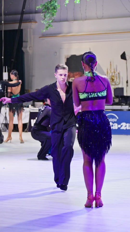 Cuplu dansând latino, rochie lila, pe ringul de concurs